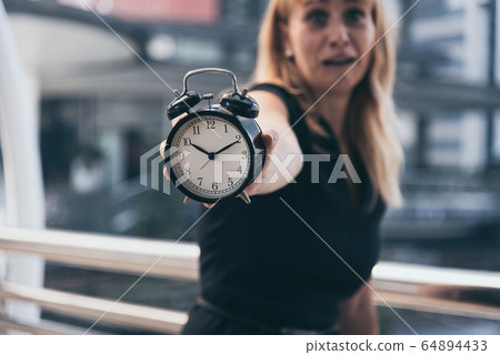 Business women show alarm clock and shocked with 64894433