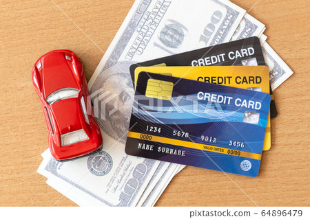 Toy car, credit cards and dollars on wooden table. Toy car, credit cards and dollars on wooden table. 64896479