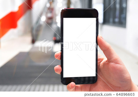 Hand holding mobile phone on escalator background. Focus on the hand. Concept of using mobile apps. Hand holding mobile phone on escalator background. Focus on the hand. Concept of using mobile apps. 64896603