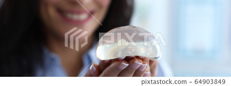 Smiling female holding implant Smiling female holding implant 64903849