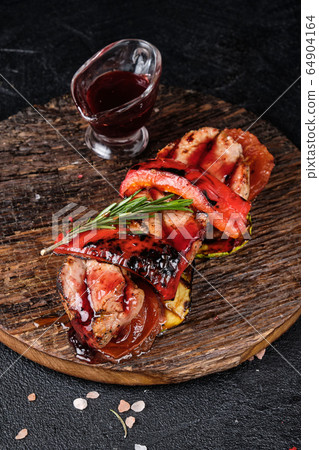 Grilled veal and grilled vegetables on a cutting board and cherry sauce on a dark concrete background 64904164