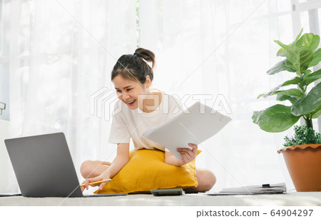 woman working for laptop with graph documents from home on the carpet. 64904297