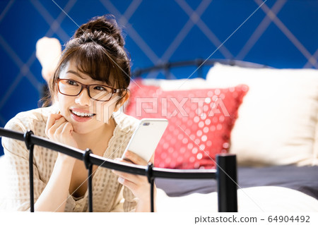 Female bedroom bed smartphone room wear smile Female bedroom bed smartphone room wear smile 64904492