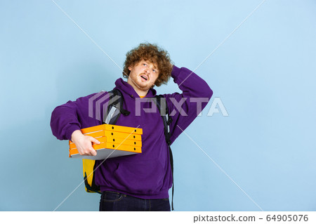 Contacless delivery service during quarantine. Man delivers food and shopping bags during insulation. Emotions of deliveryman isolated on blue background. 64905076