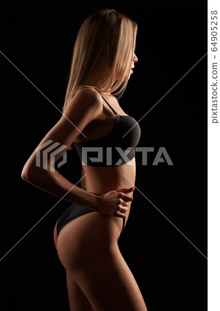 Woman in lingerie posing, holding pants. Woman in lingerie posing, holding pants. 64905258