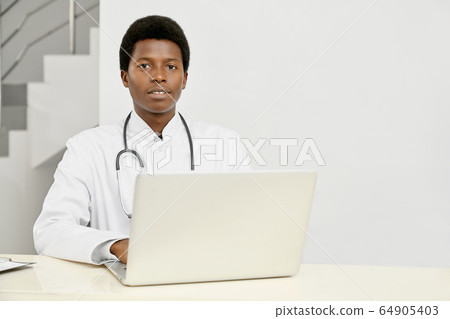 African doctor using laptop on reception. African doctor using laptop on reception. 64905403