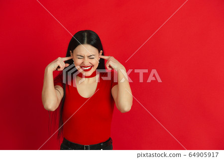Caucasian young woman's monochrome portrait on red studio background, emotional and expressive Caucasian young woman's monochrome portrait on red studio background, emotional and expressive 64905917