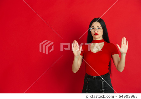 Caucasian young woman's monochrome portrait on red studio background, emotional and expressive Caucasian young woman's monochrome portrait on red studio background, emotional and expressive 64905965