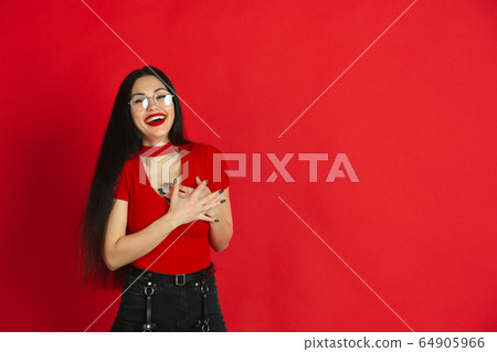 Caucasian young woman's monochrome portrait on red studio background, emotional and expressive 64905966