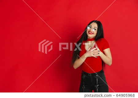 Caucasian young woman's monochrome portrait on red studio background, emotional and expressive Caucasian young woman's monochrome portrait on red studio background, emotional and expressive 64905968