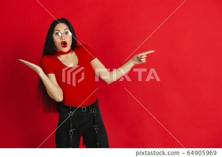 Caucasian young woman's monochrome portrait on red studio background, emotional and expressive 64905969