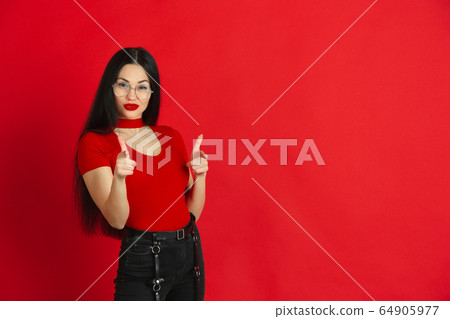 Caucasian young woman's monochrome portrait on red studio background, emotional and expressive 64905977