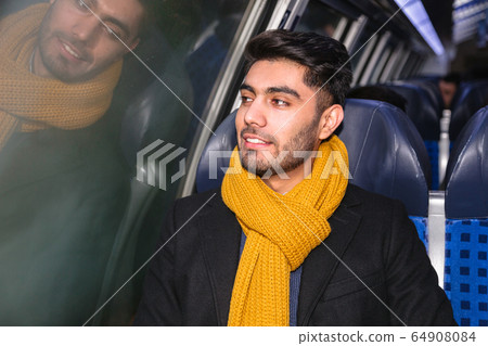 Handsome young man in train looking in window Handsome young man in train looking in window 64908084