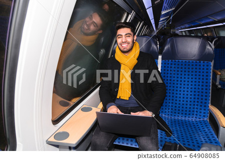 Arab man in train holds laptop and looks at camera 64908085