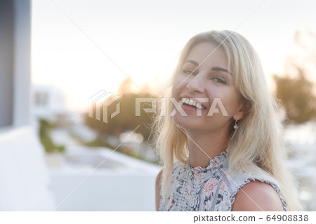 Beautiful young blond woman outdoors portrait near 64908838