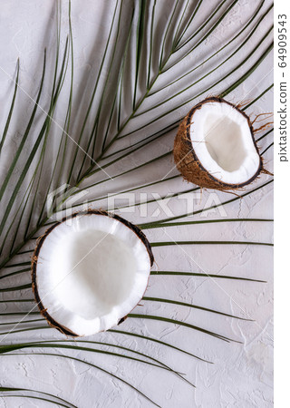 Two halves of coconut on palm leaf and on table Two halves of coconut on palm leaf and on table 64909543