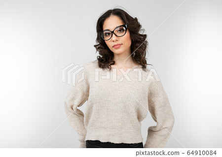 attractive brunette girl in stylish glasses for vision poses on a gray background 64910084