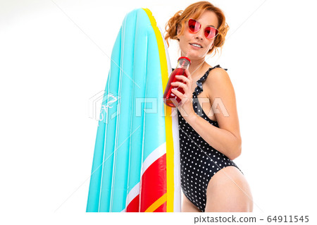 beach party concept, girl drinks a cocktail in a retro bathing suit and holds a surfboard 64911545