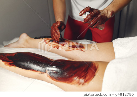 The doctor massages the woman with a chocolate 64912790