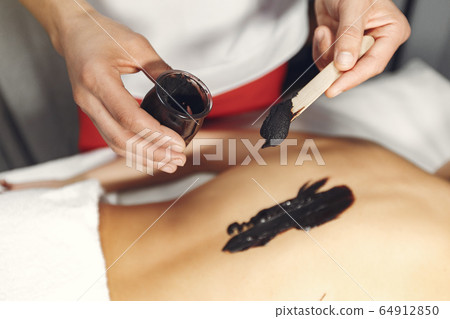 The doctor massages the woman with a chocolate 64912850