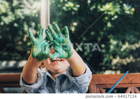Boy with hands painted in green paints ready to make hand prints 64917114