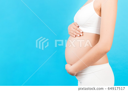 Cropped image of pregnant woman wearing white Cropped image of pregnant woman wearing white 64917517