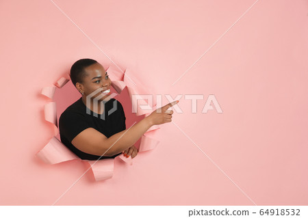 Cheerful young woman poses in torn coral paper hole background, emotional and expressive Cheerful young woman poses in torn coral paper hole background, emotional and expressive 64918532
