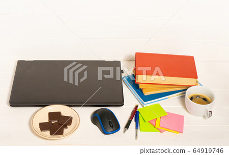 Home office concept. Work from home. Black laptop, books and cafe cuo on the white wooden background. Side view. Home office concept. Work from home. Black laptop, books and cafe cuo on the white wooden background. Side view. 64919746
