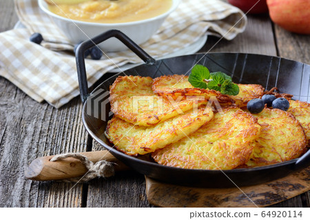 Homemade and crispy fried potato pancakes served in an iron pan with apple sauce 64920114