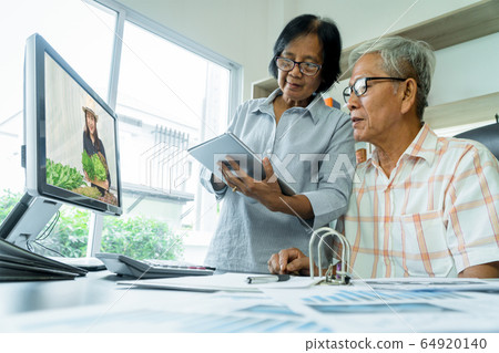 Asian senior couple using tablet and computer for 64920140