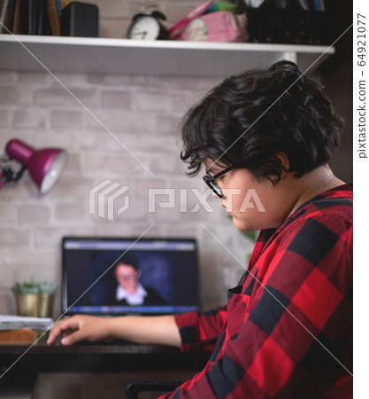 Sad teenage girl is learning remotely 64921077