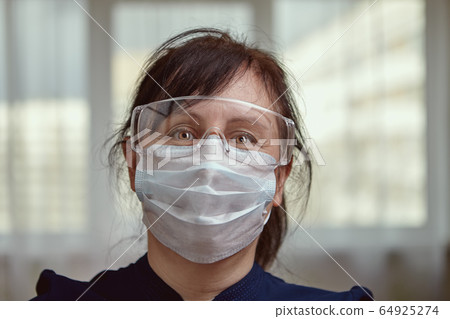 A woman uses PPE during self-isolation in her A woman uses PPE during self-isolation in her 64925274