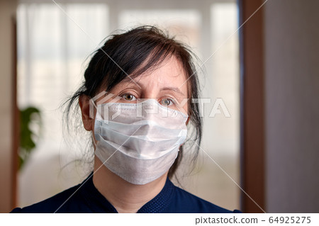 A woman uses a surgical mask for self-isolation. A woman uses a surgical mask for self-isolation. 64925275