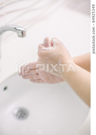 Woman washes her hands by surgical hand washing method. She washes his hands for at least 20 seconds. 64925349