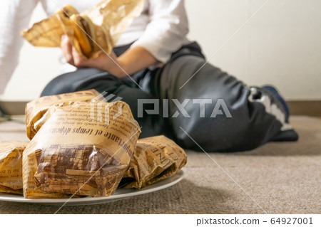 Image of a woman eating a hamburger lying on the floor 64927001