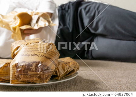 女人吃漢堡包躺在地板上的圖像 64927004