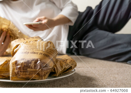 女人吃漢堡包躺在地板上的圖像 64927008