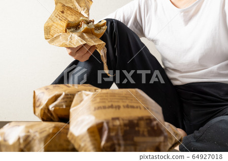 女人吃漢堡包躺在地板上的圖像 64927018