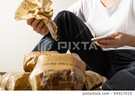 女人吃漢堡包躺在地板上的圖像 64927019