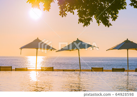 Beautiful tropical outdoor beach sea ocean with umbrella and chiar around outdoor swimming pool at sunset or sunrise time Beautiful tropical outdoor beach sea ocean with umbrella and chiar around outdoor swimming pool at sunset or sunrise time 64928598