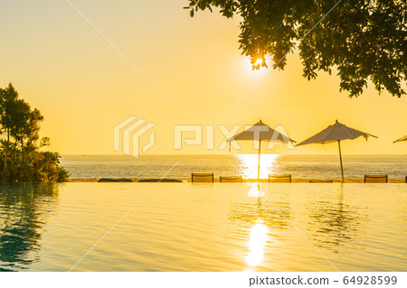 Beautiful tropical outdoor beach sea ocean with umbrella and chiar around outdoor swimming pool at sunset or sunrise time Beautiful tropical outdoor beach sea ocean with umbrella and chiar around outdoor swimming pool at sunset or sunrise time 64928599