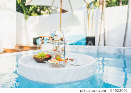 Breakfast and afternoon tea set floating around swimming pool Breakfast and afternoon tea set floating around swimming pool 64928601