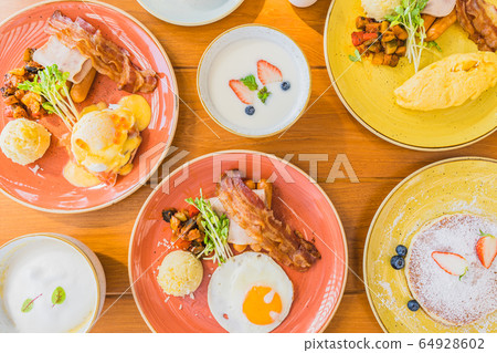 Fried egg with eggs benedict and omelette around bacaon ham sausage in plate Fried egg with eggs benedict and omelette around bacaon ham sausage in plate 64928602