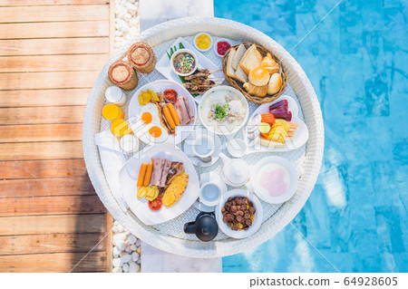 Floating breakfast set in tray with fried egg omelette sausage ham bread fruit milk juice coffee Floating breakfast set in tray with fried egg omelette sausage ham bread fruit milk juice coffee 64928605