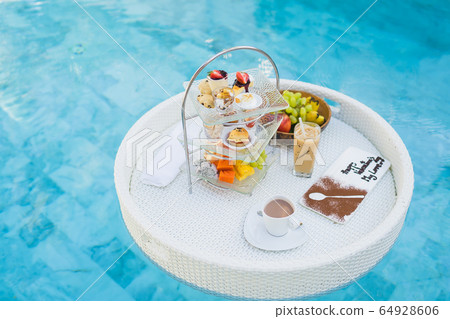 Breakfast and afternoon tea set floating around swimming pool Breakfast and afternoon tea set floating around swimming pool 64928606