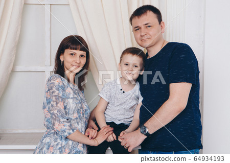 Warming and relaxing. Mother, father and son hugging. Concept of family , motherhood, interior, home, childhood, mother's day, children's day 64934193