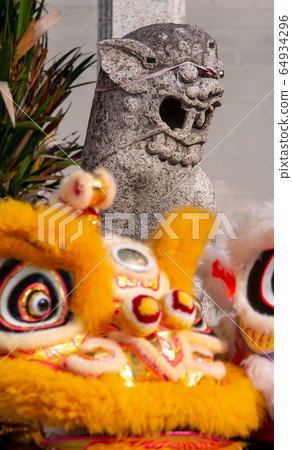 Old lion statue with front lion dance in front of Old lion statue with front lion dance in front of 64934296