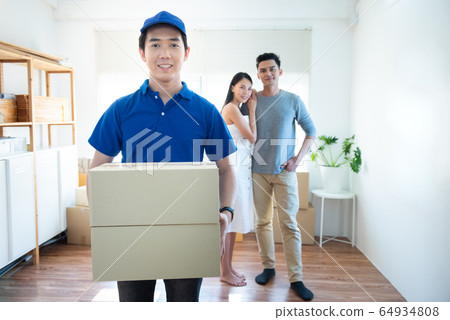 Smiling young asian delivery man in blue uniform Smiling young asian delivery man in blue uniform 64934808