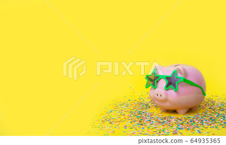 A pink piggy bank in fun green glasses at a party. Yellow background. A pink piggy bank in fun green glasses at a party. Yellow background. 64935365