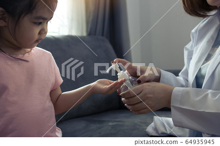 Female pediatrician is holding a bottle of alcohol 64935945
